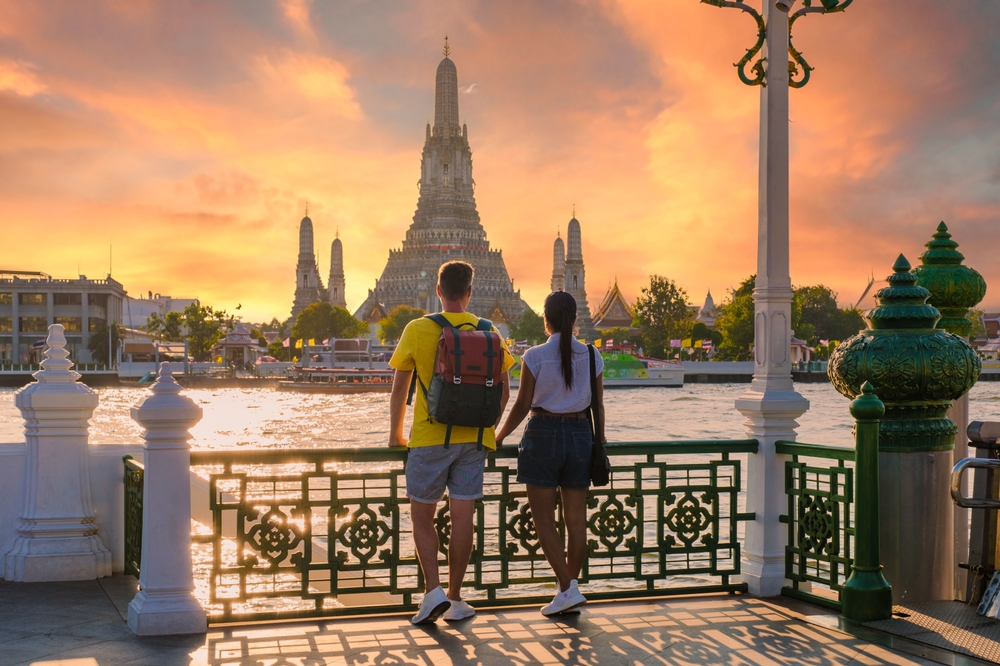 A couple looks out at a temple at dusk. There are plenty of places to visit in Bangkok for couples.